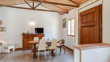 A dining area with a wooden ceiling, a TV on a wooden cabinet, and a window with a view.