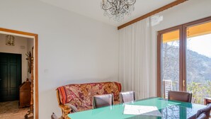 Et spiseområde med et bord med glasplade, træstole og en sofa med et mønster.