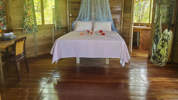 Ein Schlafzimmer einer Holzhütte mit einem Bett, einem Schreibtisch und einem Stuhl.