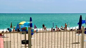 Una playa con cercas, sombrillas y gente.