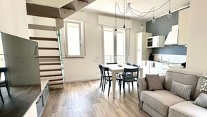 Un apartamento moderno con comedor, cocina, escalera y sala de estar.