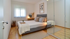A bedroom with a bed, bedside table, lamp, and a framed picture on the wall.