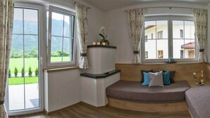 Une chambre dotée d’un lit à la forme arrondie, de grandes fenêtres et offrant une vue sur la verdure et les bâtiments.