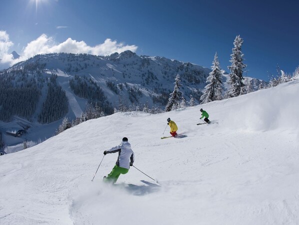 A snowy mountain slope with skiers.