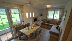 A modern kitchen with a dining table, chairs, a built-in bench, and large windows offering a view of the outdoors.