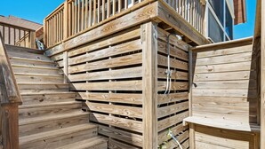 A wooden deck with a built-in bench and a small table, surrounded by vertical wooden slats. - Spacious Second-Row Home Across from Beach Access (Georgetown)