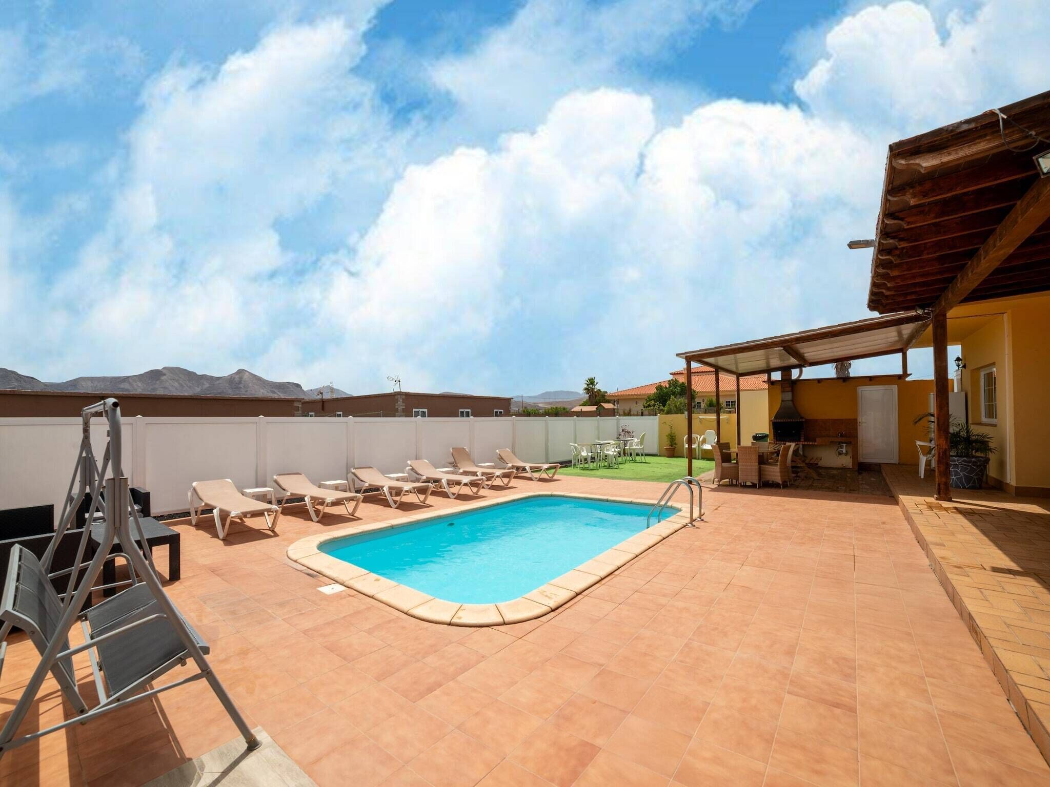 Una piscina en la azotea con sillones de descanso, zona de barbacoa y vistas a las montañas.
