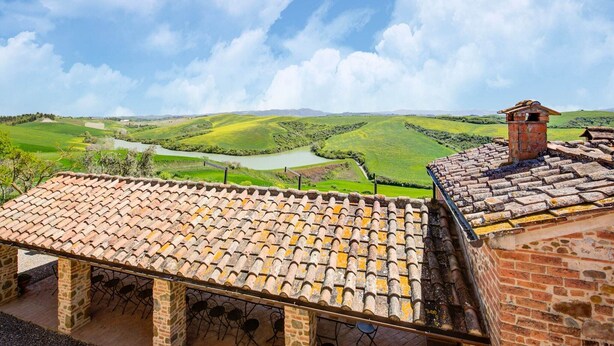 A terracotta-tiled roof, stone walls, and a view of rolling green hills and a river. - Apartment in Peccioli with Pool and Wine Tasting (Peccioli)