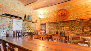 A rustic bar area with stone walls, wooden tables, and a variety of wine bottles. - Apartment in Peccioli with Pool and Wine Tasting (Peccioli)