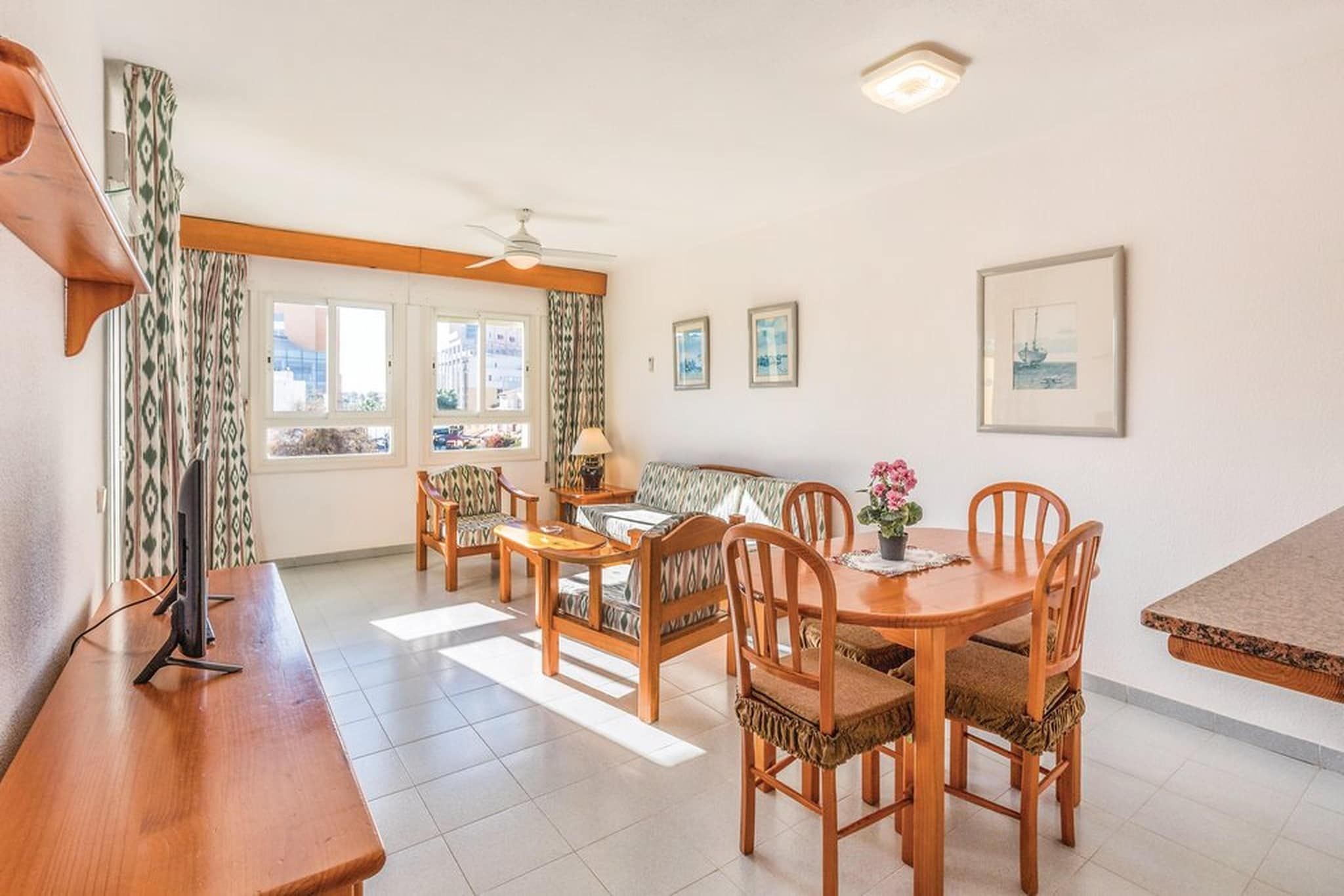 A dining area with a wooden table and chairs, a sofa, and a ceiling fan.