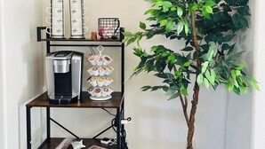 Eine Kaffeestation mit Kaffeemaschine, Tassenhalterung und einem kleinen Blumentopf.