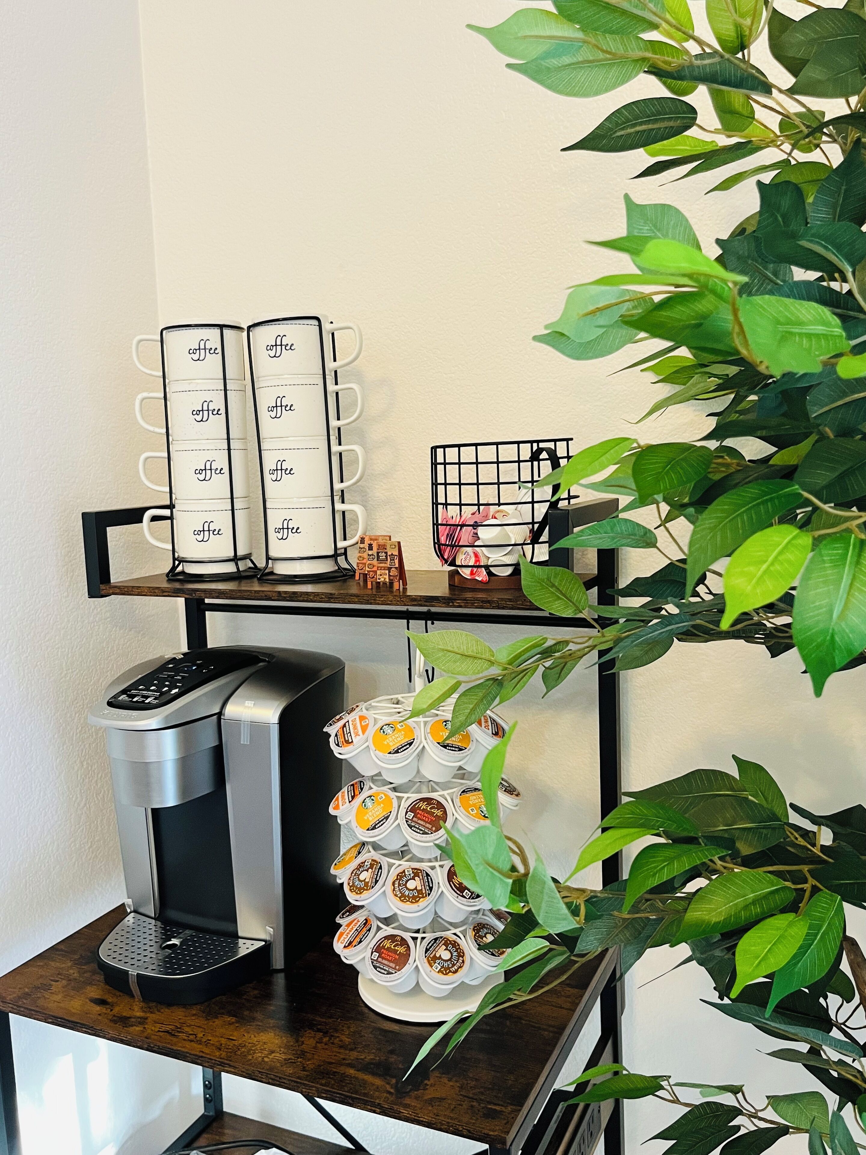 A coffee station with a coffee maker, a mug rack, and a McCafe display.