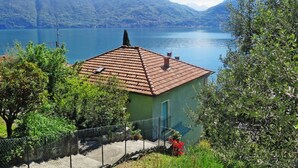 Ein Haus mit Ziegeldach, umgeben von Grün und mit Blick auf ein Gebirge.