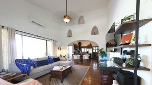 A spacious living area with a sofa, coffee table, and a dining area in the background.