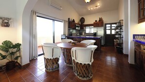 A spacious kitchen with a dining area, featuring a large window, a ceiling fan, and a tiled floor.