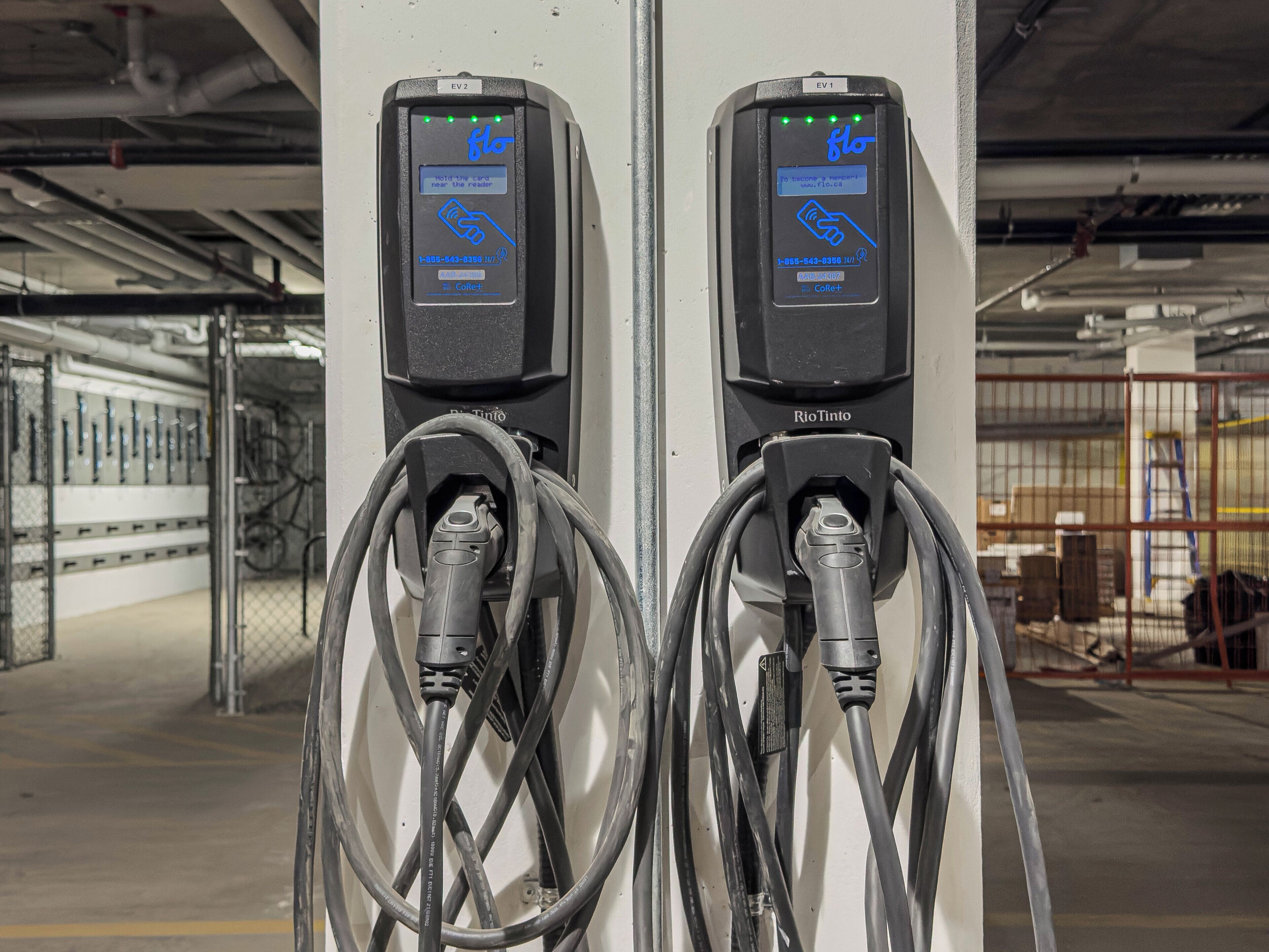 Two EV charging stations with digital displays, connected to a network of cables.