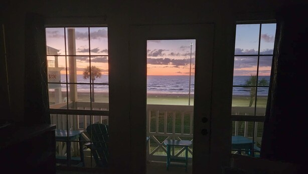 A view from a room with a door leading to a balcony overlooking a beach at sunset. - Beach Hair; Don't Care - Waves, Views, and Zero Worries! (Galveston)