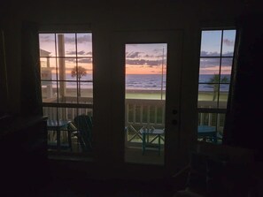 A view from a room with a door leading to a balcony overlooking a beach at sunset. - Beach Hair; Don't Care - Waves, Views, and Zero Worries! (Galveston)