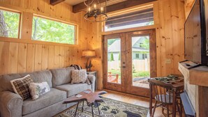 A cozy cabin interior with a wooden interior, a sofa, a dining table, and a television.