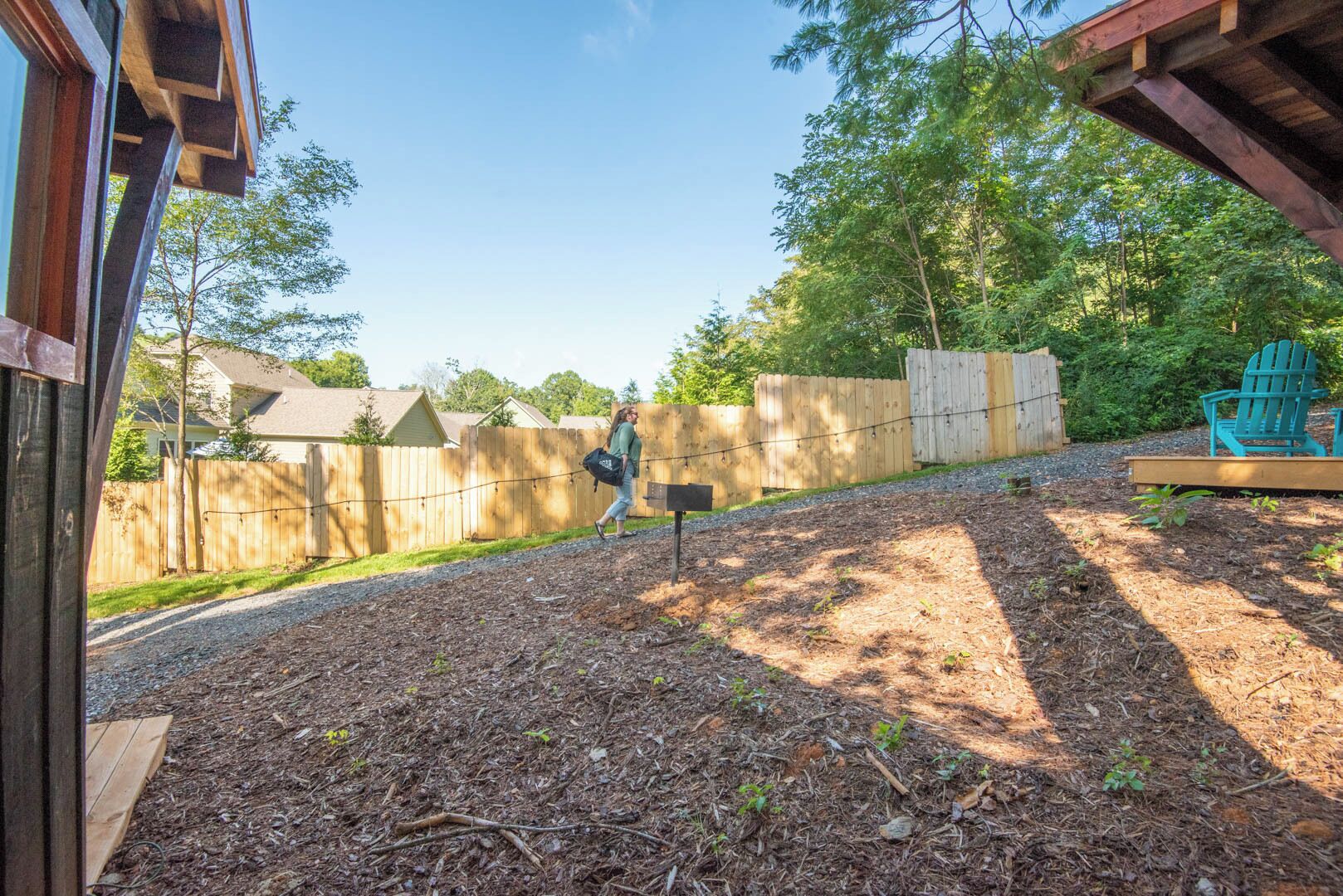 A backyard with a wooden deck, a swing set, and a wooden fence.
