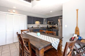 A kitchen with dark cabinets, a microwave, stove, and a dining table with chairs. - 3 Bedroom Osage Beach Condo w/ Pool & Main Channel Views (Osage Beach)