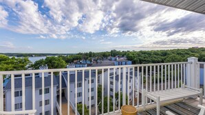 A balcony with a view of a lake, buildings, and a clear sky.