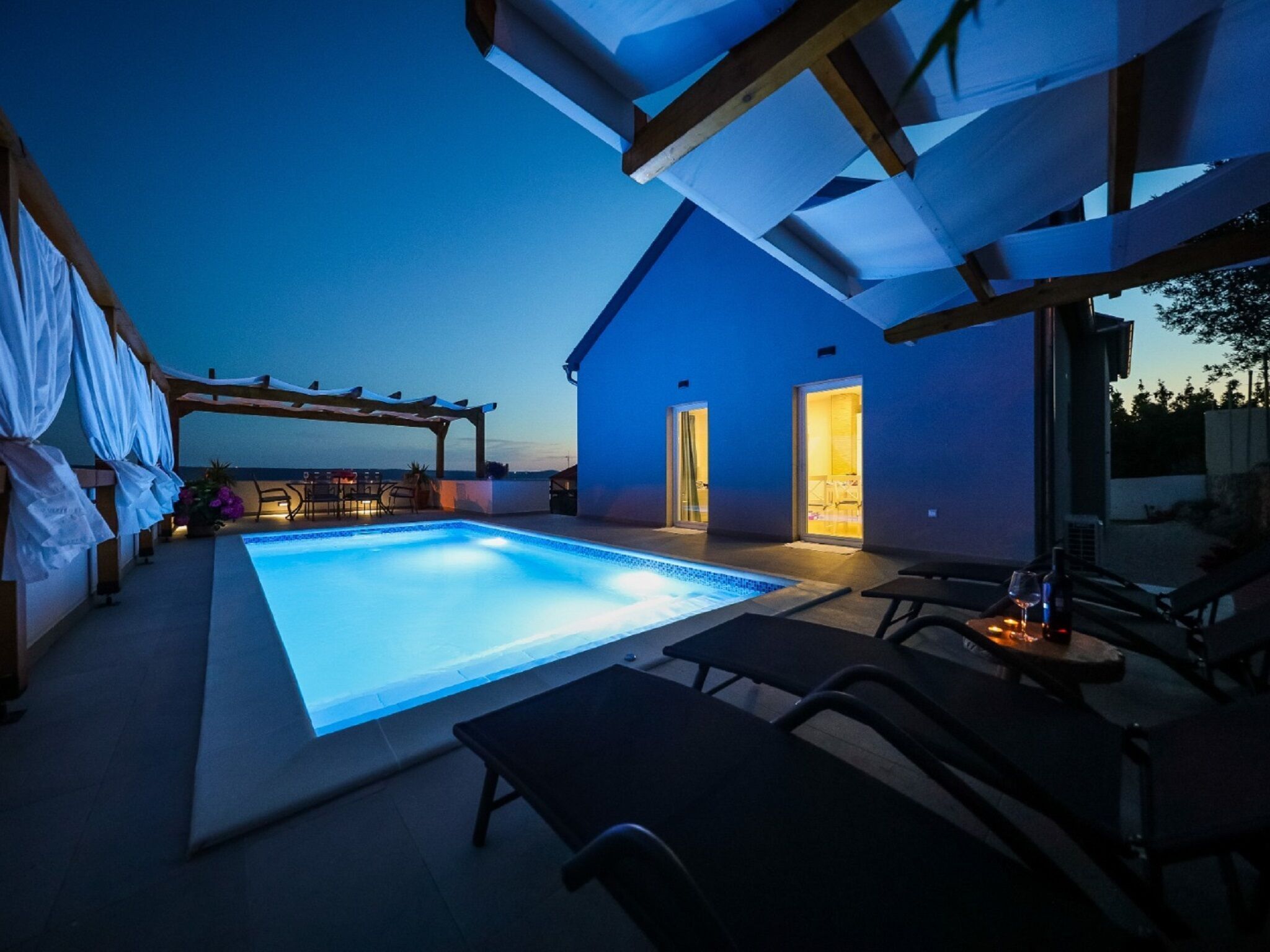 Ein Swimmingpool mit Pergola und einer Sitzgelegenheit im Freien.