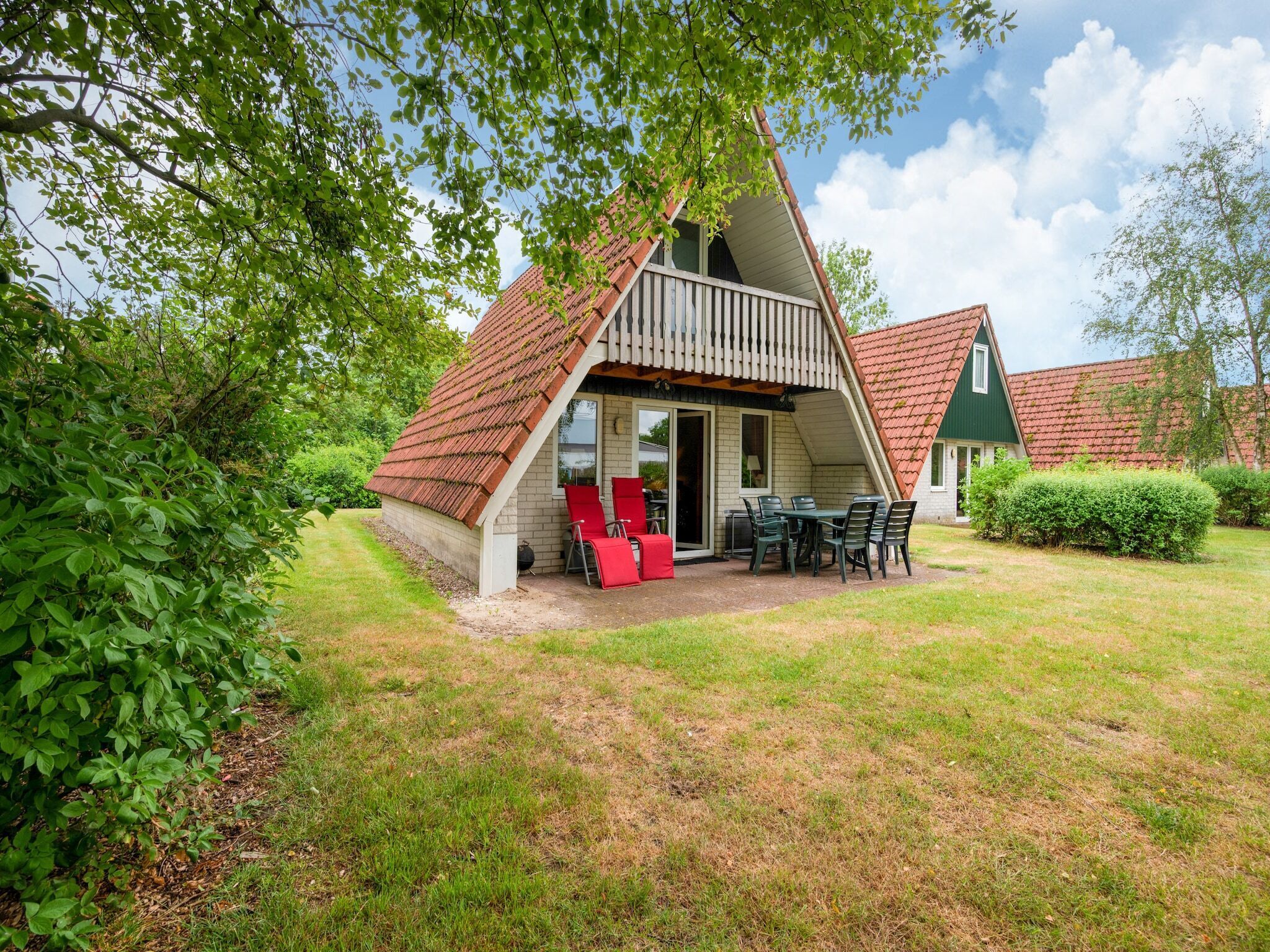 Un petit bâtiment de forme triangulaire, doté d’une terrasse, de sièges extérieurs et offrant une vue sur la végétation environnante.