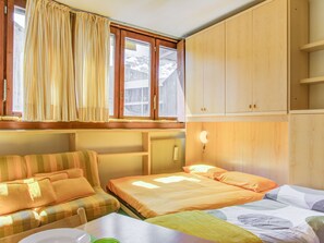 A room with a bed, a sofa, a table, and a window with curtains.