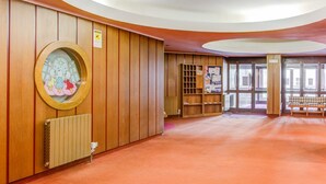 A spacious room with wooden paneling, a large circular window with a star decoration, a radiator, and a bench.