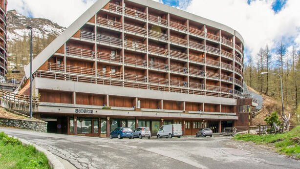 A multi-story hotel with a unique architectural design, featuring balconies and a ski resort sign.