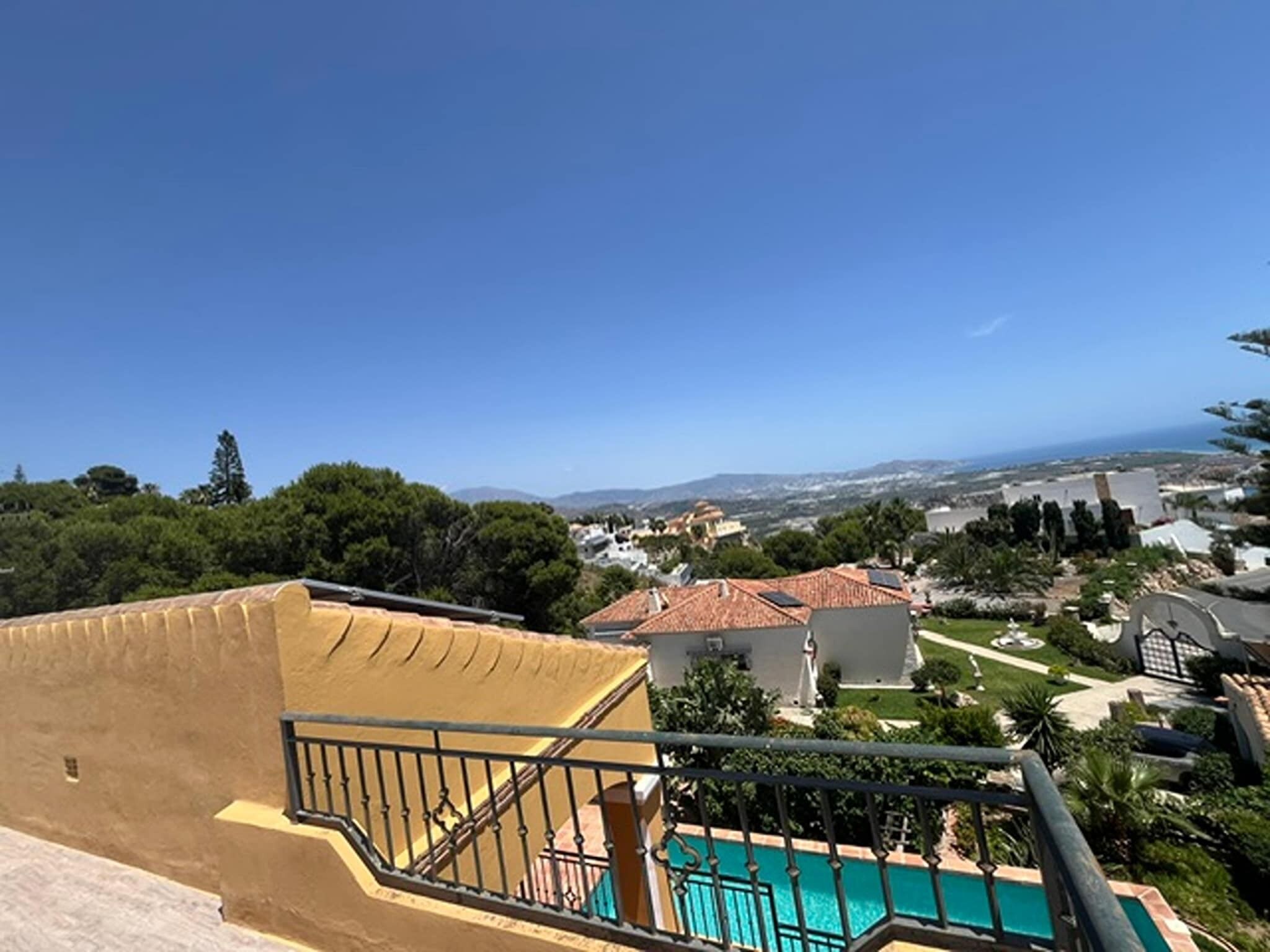 A residential area with a clear view of a swimming pool, a staircase, and surrounding greenery.
