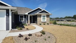 A modern single-story house with a stone facade, a covered porch, and a landscaped front yard with gravel and small plants. - Full home available for EAA 2025. Minimum 7 day rental. (Oshkosh)