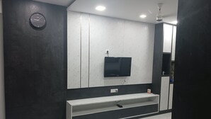 Un baño moderno con un espejo grande, un televisor montado y un banco integrado.