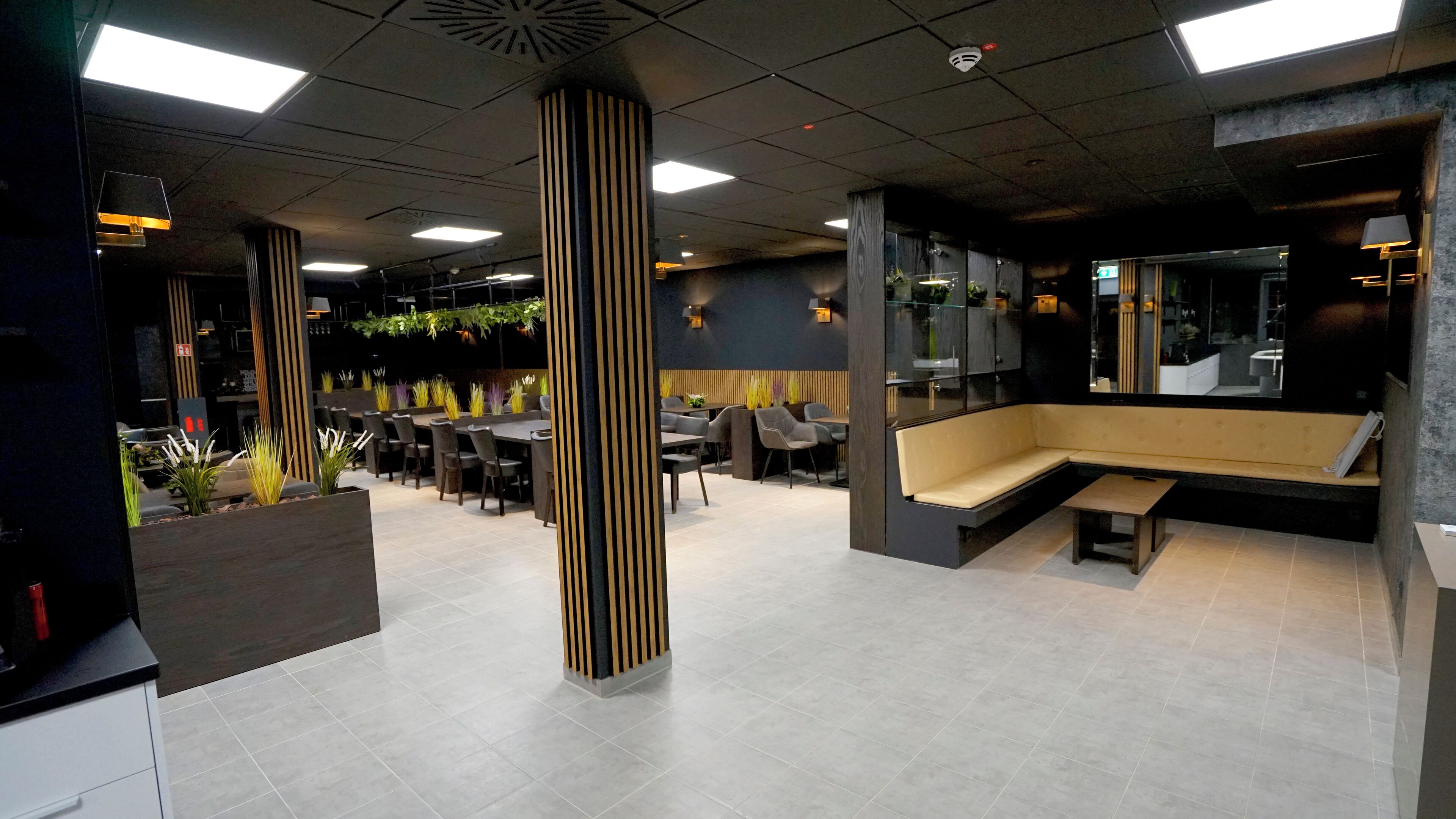 A modern indoor space with a central column, multiple seating areas, and a mix of tables and chairs.
