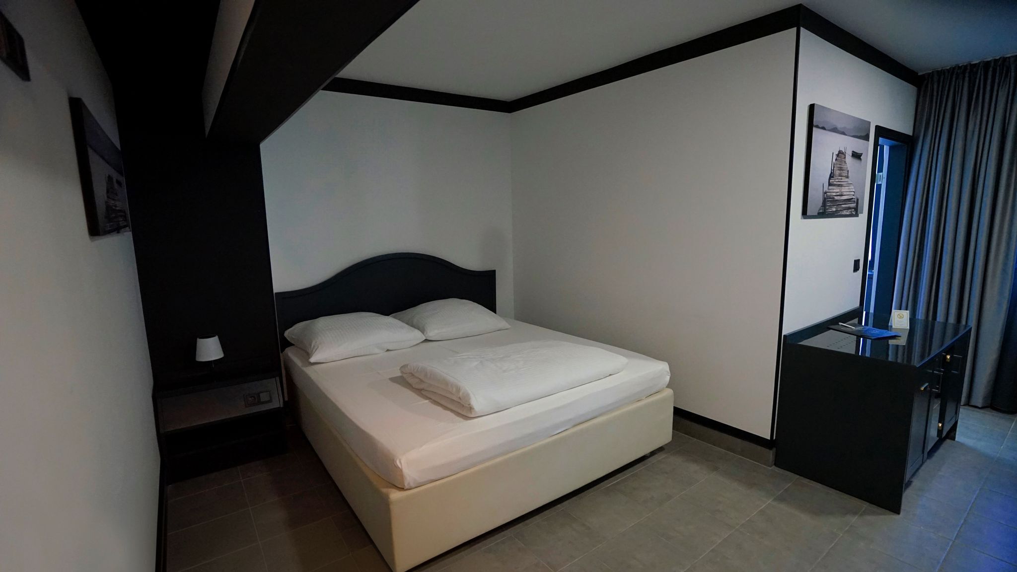 Ein Hotelzimmer mit Bett, Nachttisch, Schreibtisch und Stuhl.