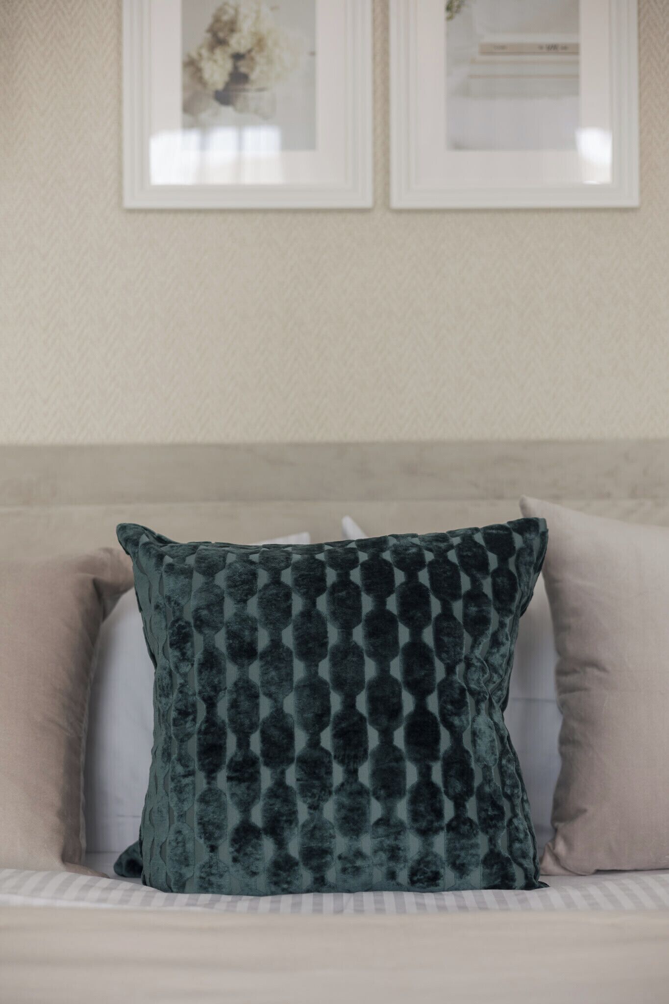 Un lit avec un oreiller à motifs verts, un oreiller beige et un oreiller blanc.