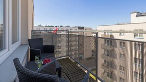 A balcony with wicker furniture, a table with drinks, and a view of neighboring buildings. - Potulicka Coffee Studio (Szczecin)