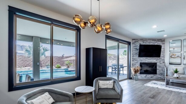 Una sala de estar moderna con ventanas amplias, chimenea y vista a la piscina.
