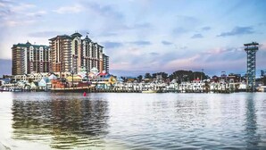 Un hôtel situé au bord de l’eau, doté de nombreux balcons, un port de plaisance avec des bateaux et une tour.