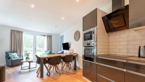 A modern kitchen with built-in appliances, a dining area with a table and chairs, and a view of the outdoors through large windows. - holiday home in Goirle with sauna (Goirle)