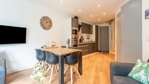 A modern living room with a wooden dining table, black chairs, a grey sofa, and a flat-screen TV mounted on the wall. - holiday home in Goirle with sauna (Goirle)