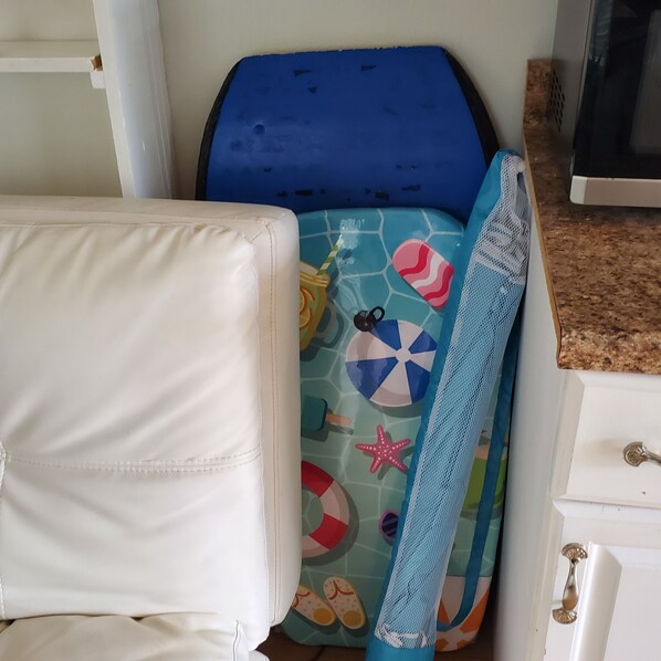 A room with a white chair, a blue and white patterned bed, and a white dresser with a metal handle.