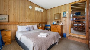 Een slaapkamer met houten lambrisering, een bed, een kapstok en een spiegel.
