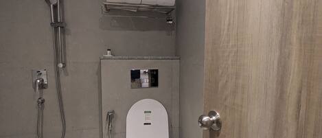A modern bathroom with a toilet, shower, and a towel rack.