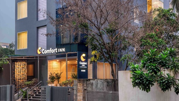 Um edifício moderno do Comfort Inn com um 'C' proeminente, janelas amplas e entrada com portão.