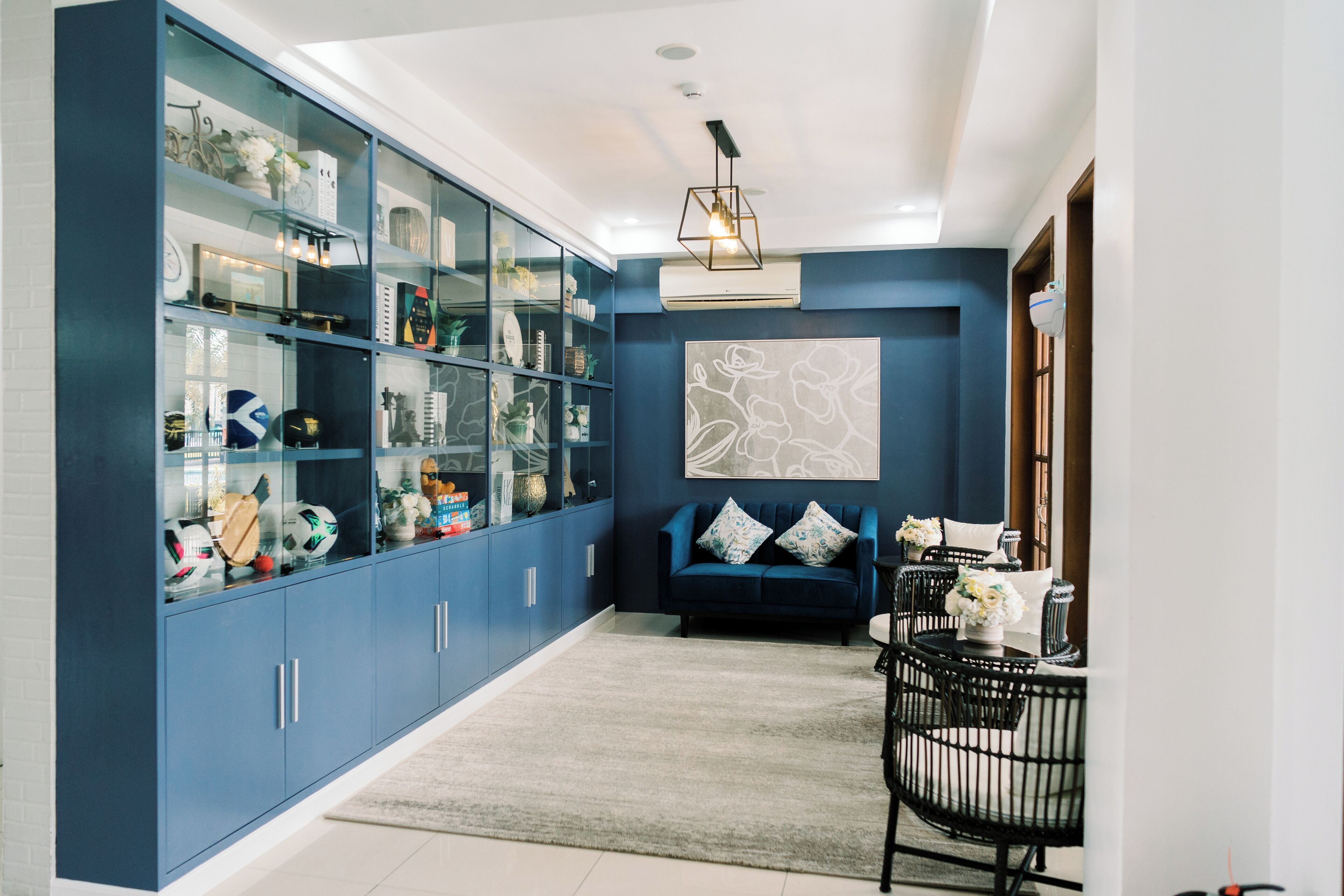 A modern living room with a blue cabinet, a blue sofa, and a dining area with black chairs.