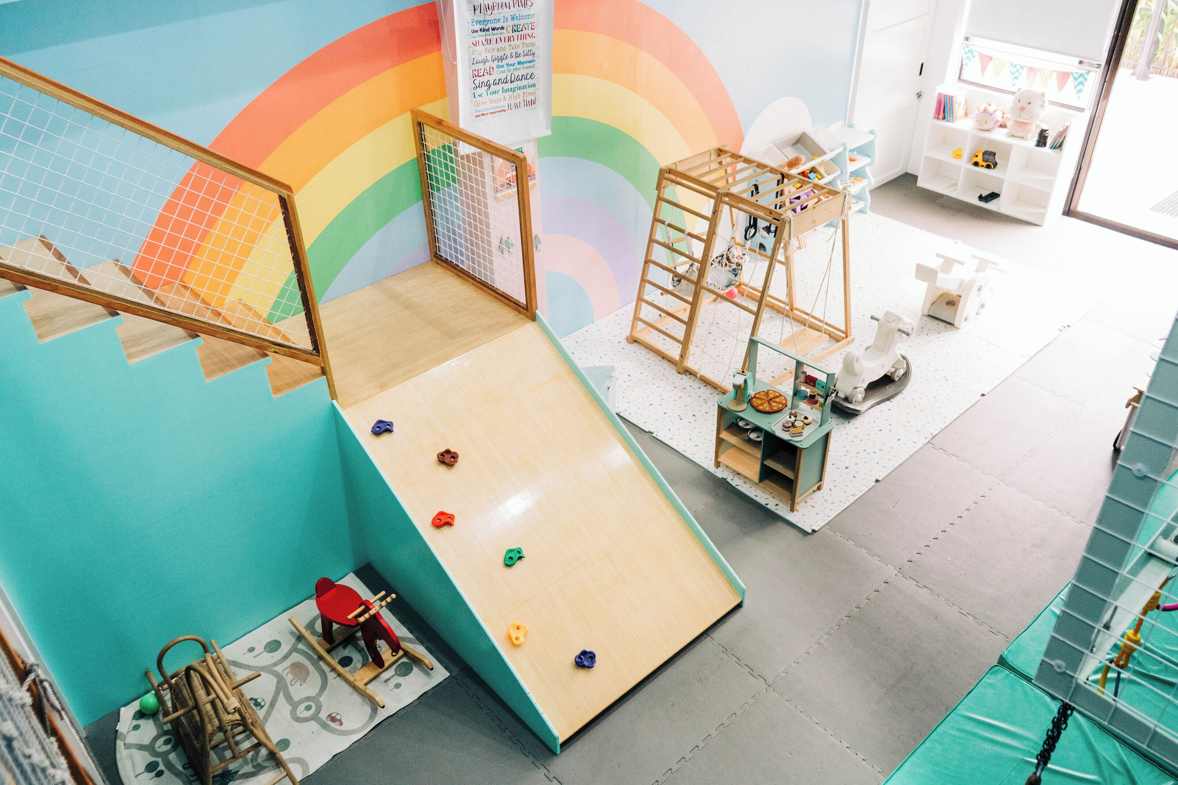 Un espace de jeux pour enfants avec un toboggan, un mur d’escalade et divers jouets.