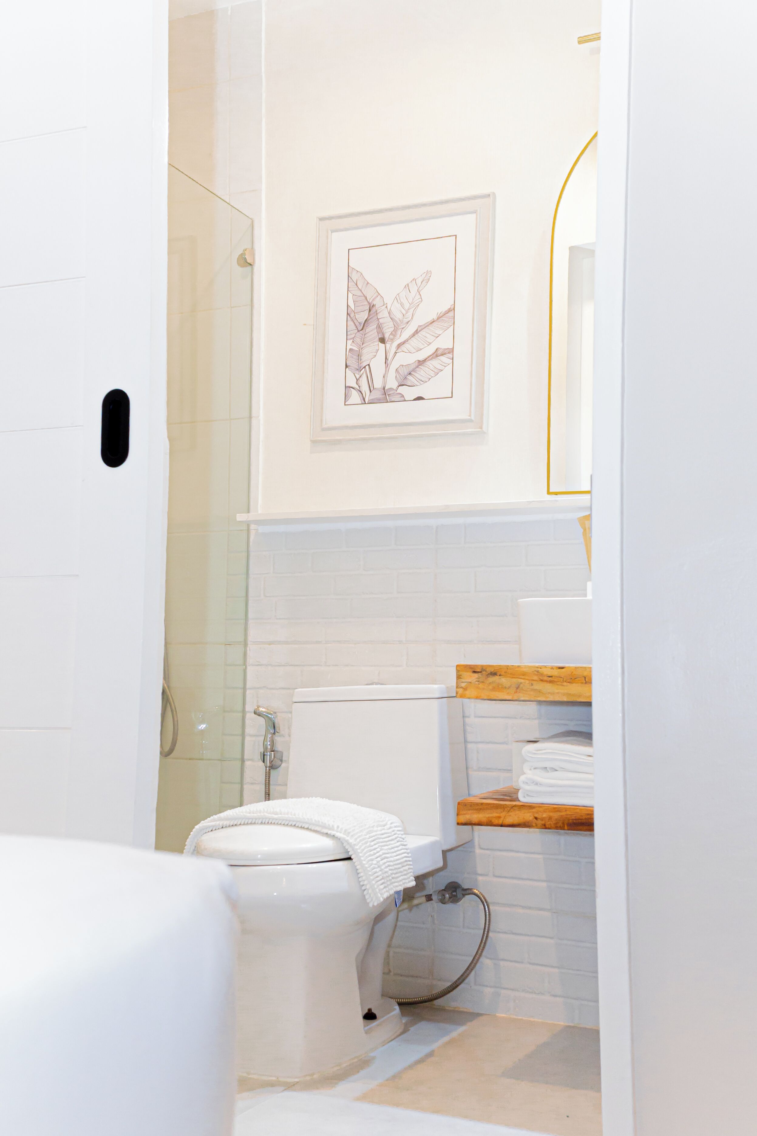Une salle de bain équipée de toilettes, d’une douche et ornée d’une illustration botanique encadrée au mur.