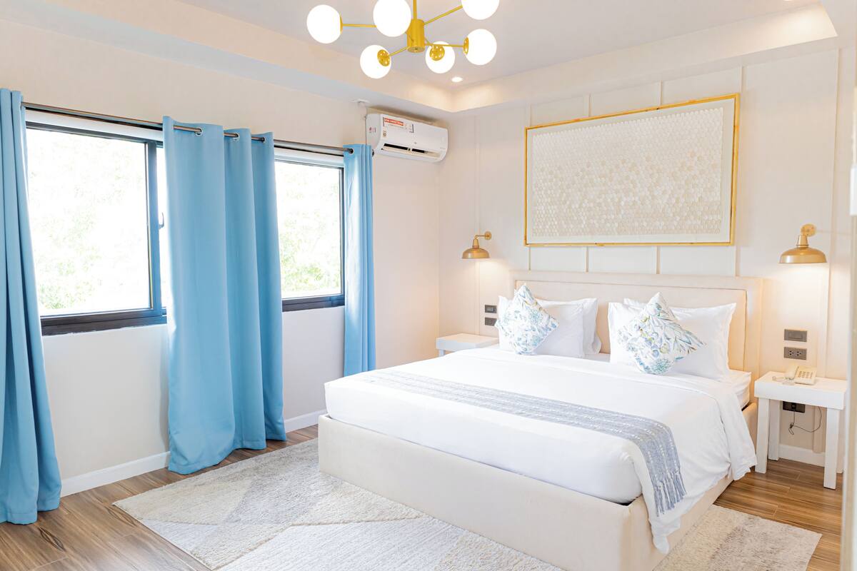 Ein modernes Schlafzimmer mit einem großen Bett, einem Nachttisch, einer Wand-Klimaanlage.
